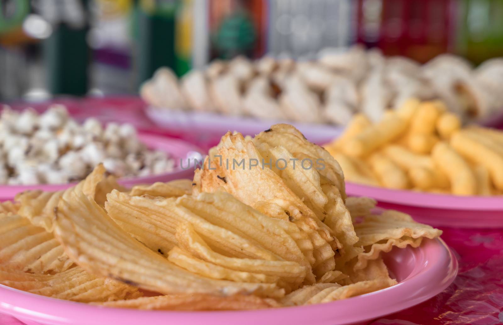 Junk food for party, birthday and every event. In the foreground wavy potato chips. On defocused background, popcorn and mini pizzas.