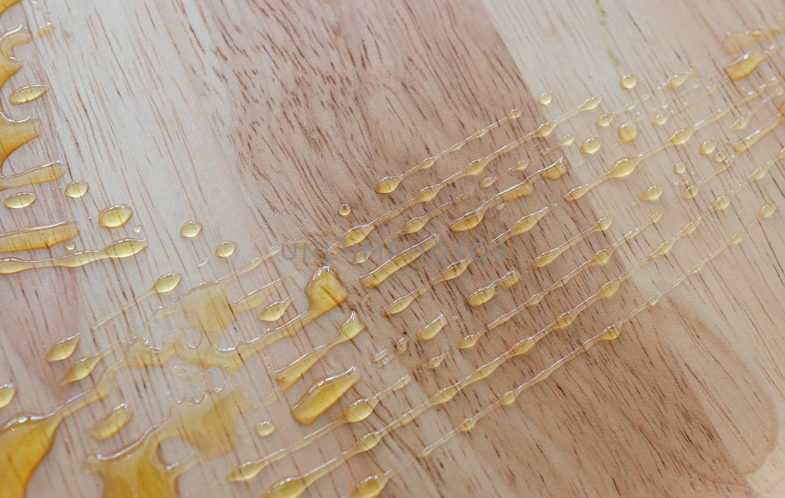 golden honey drops on natural wooden plate background