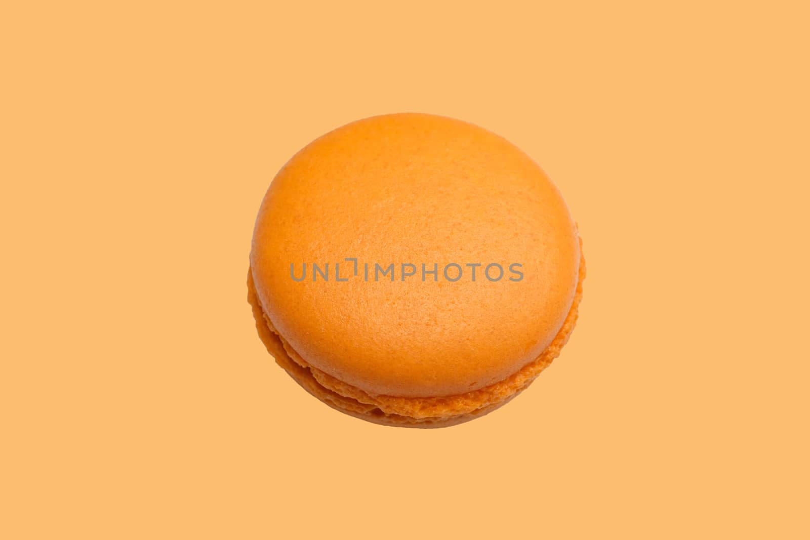 an orange flavored macaroon with chocolate filling, macro top view clean minimal style, isolated on pale orange background