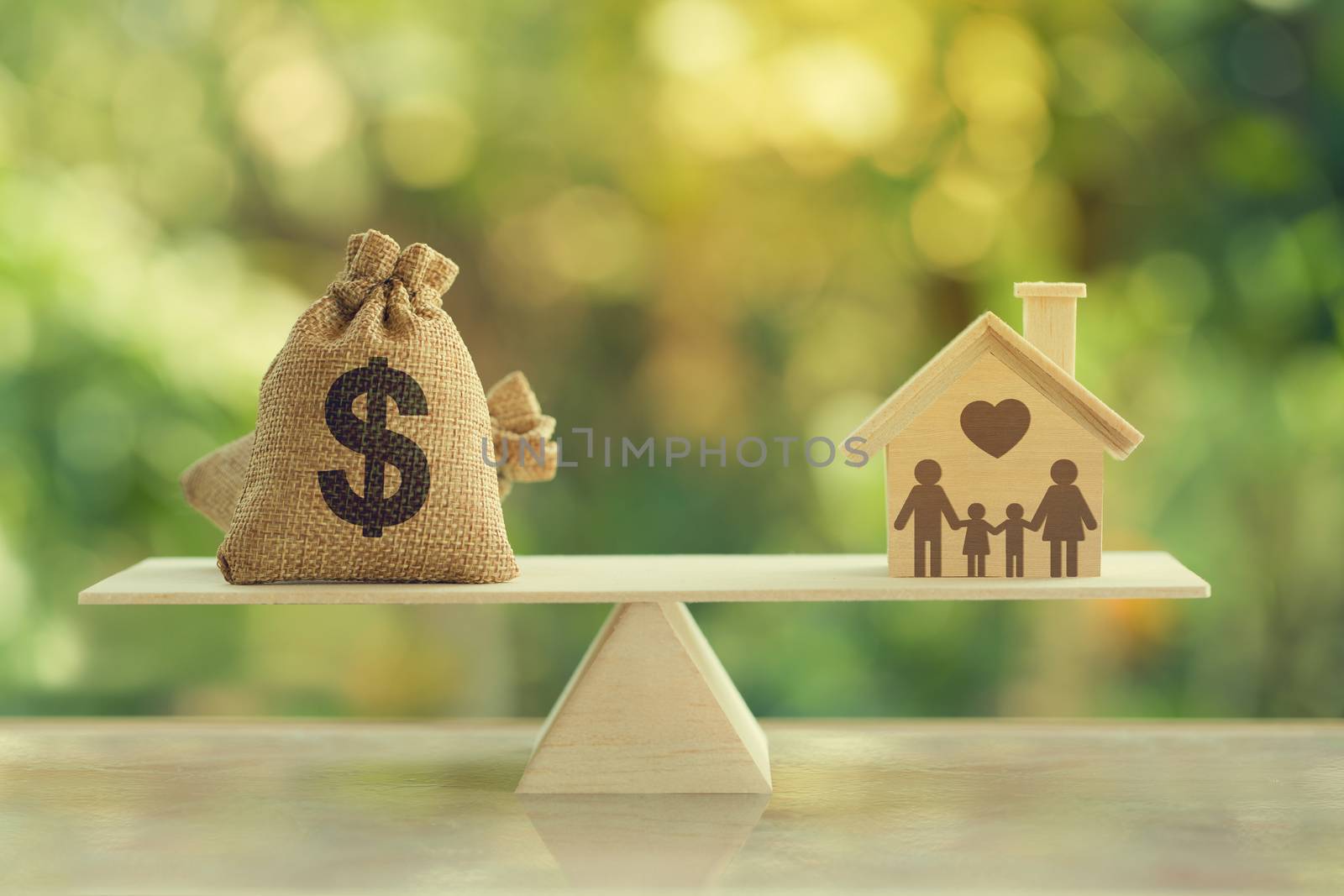 House mortgage and family financial management concept: Wooden home and heart, Family member and US dollar hessian bags on balance scale. Prepare expenses for the purchase of a residence.
