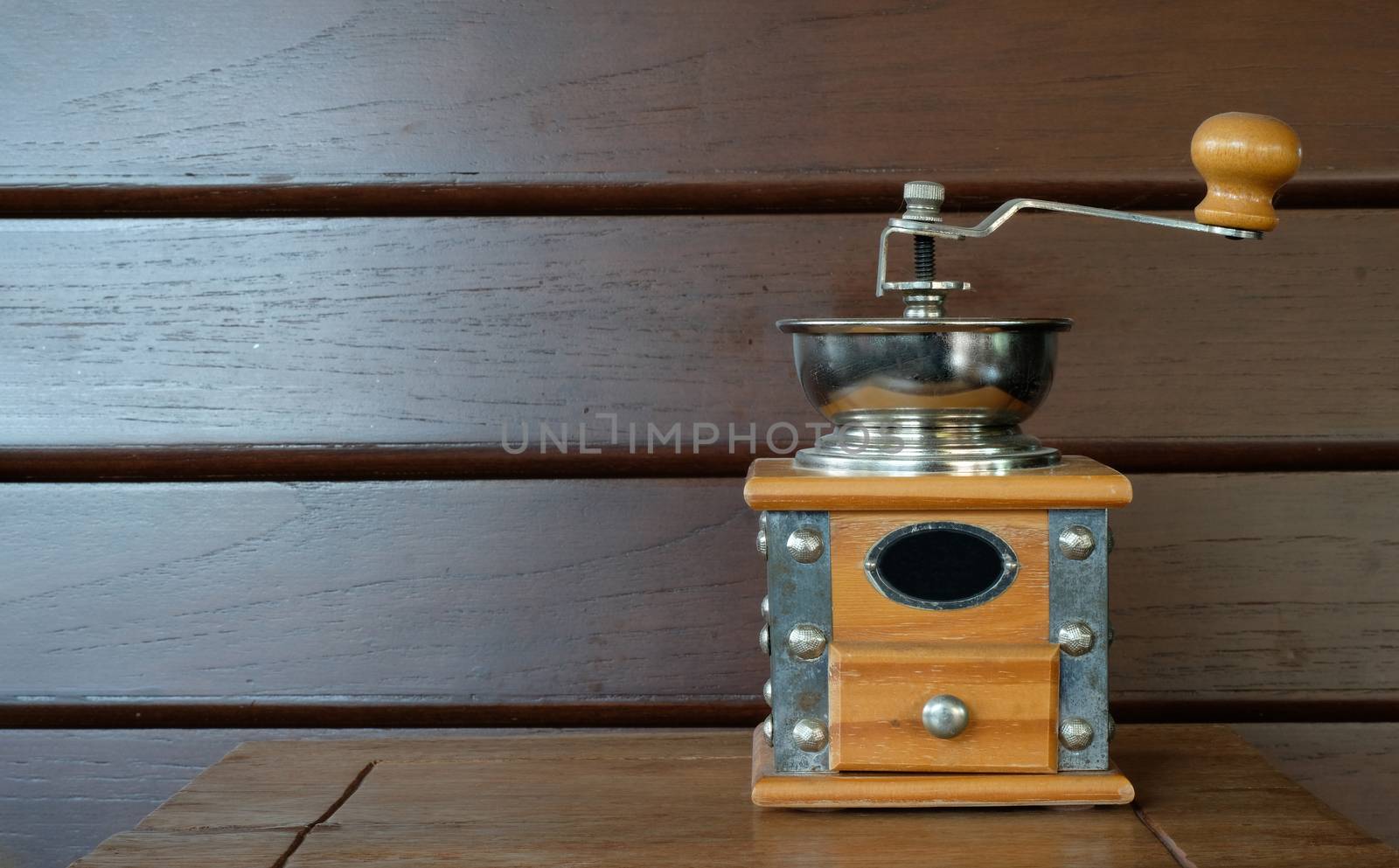vintage coffee grinder with a metal bow on a wooden table and wall background