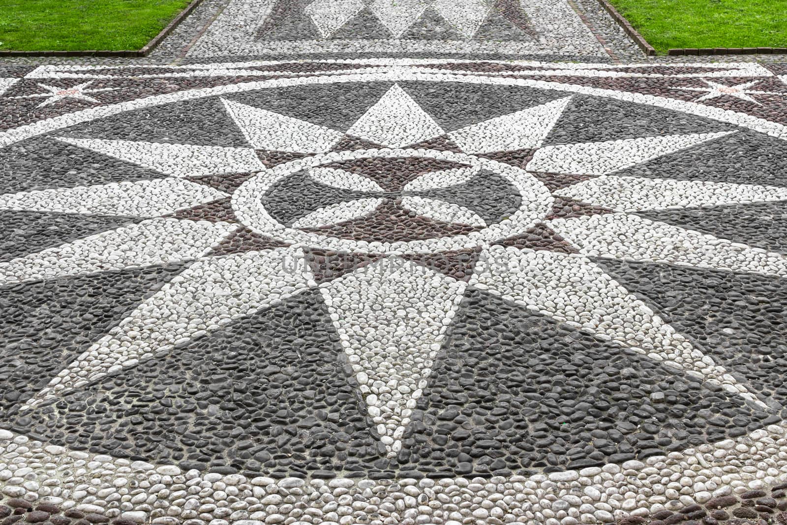 A stone mosaic depicting a twelve-pointed star, located at the entrance of a church.