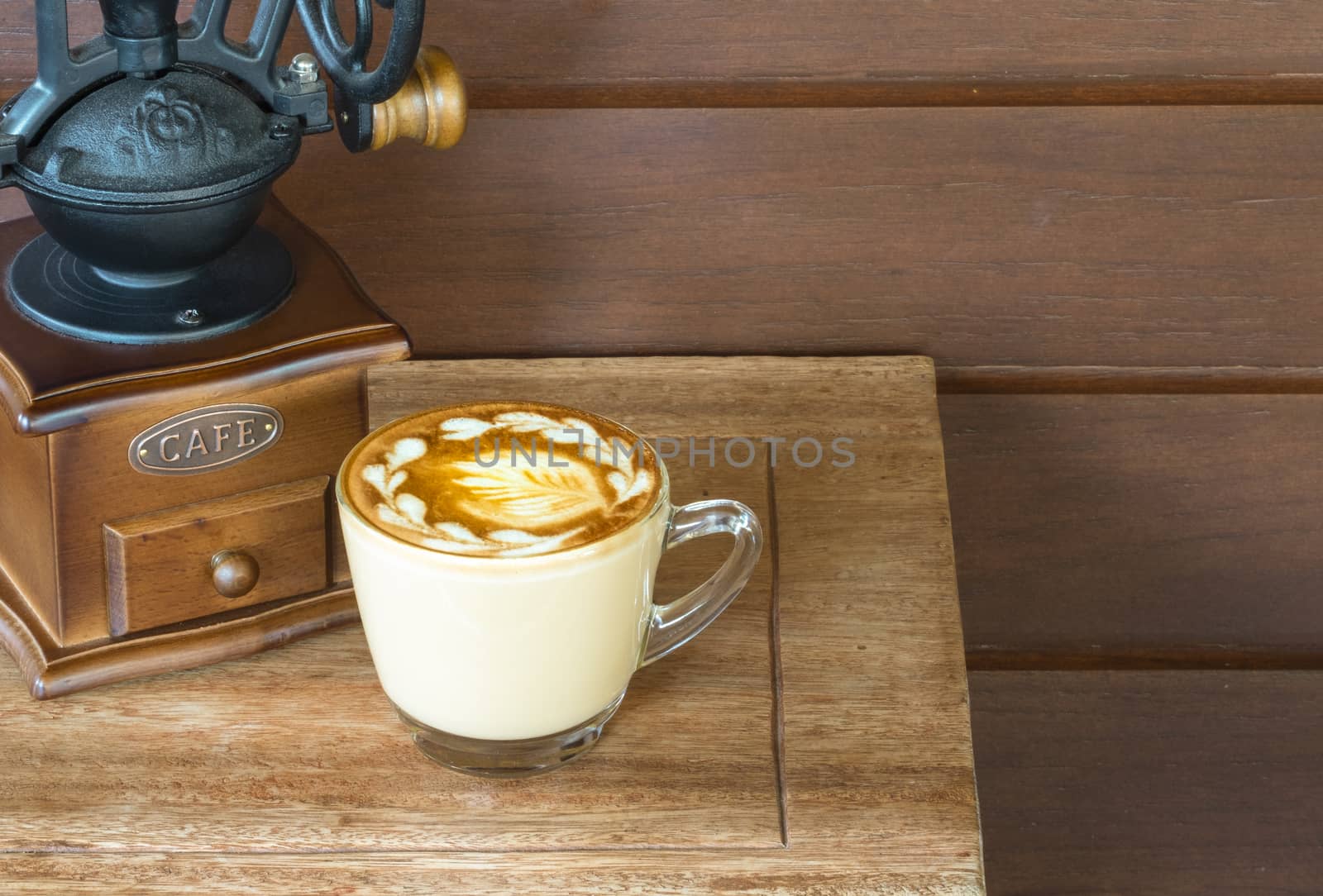 a cup of warm coffee latte on a small wooden table in a cozy room