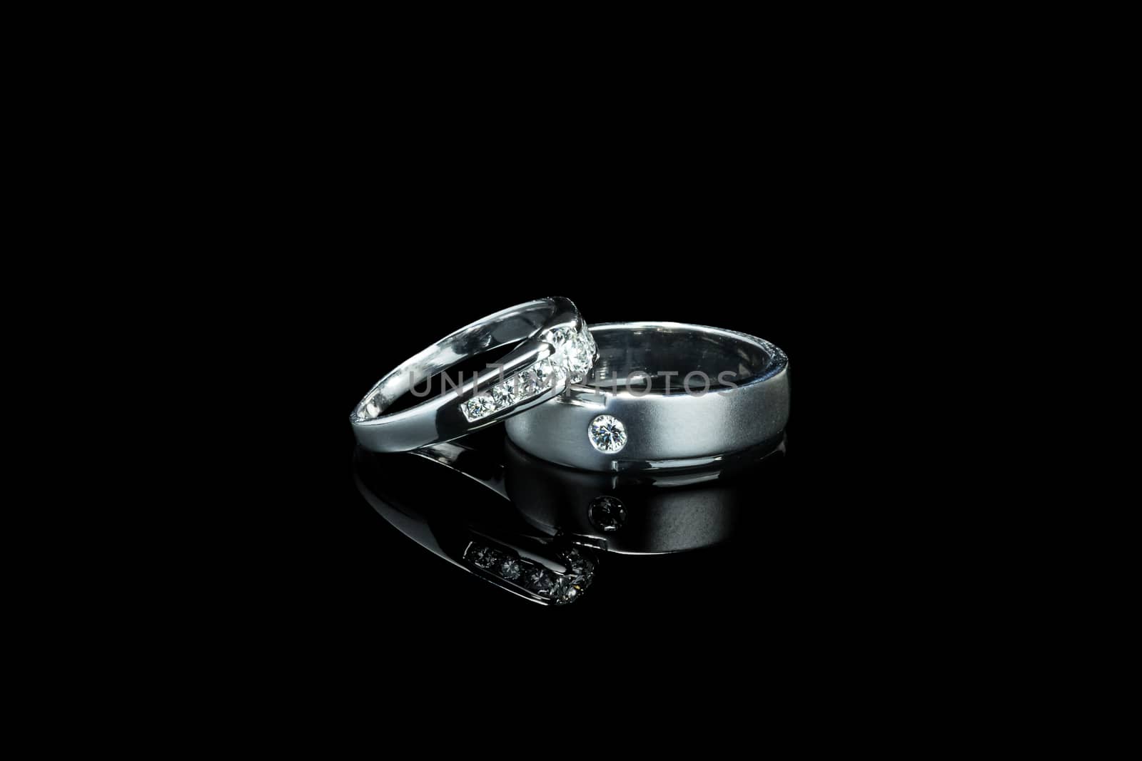 couple of luxury wedding diamond rings for bride and groom isolated on black background with shadow reflection and copy space. couple ring for wedding and engagement ceremony concept by asiandelight