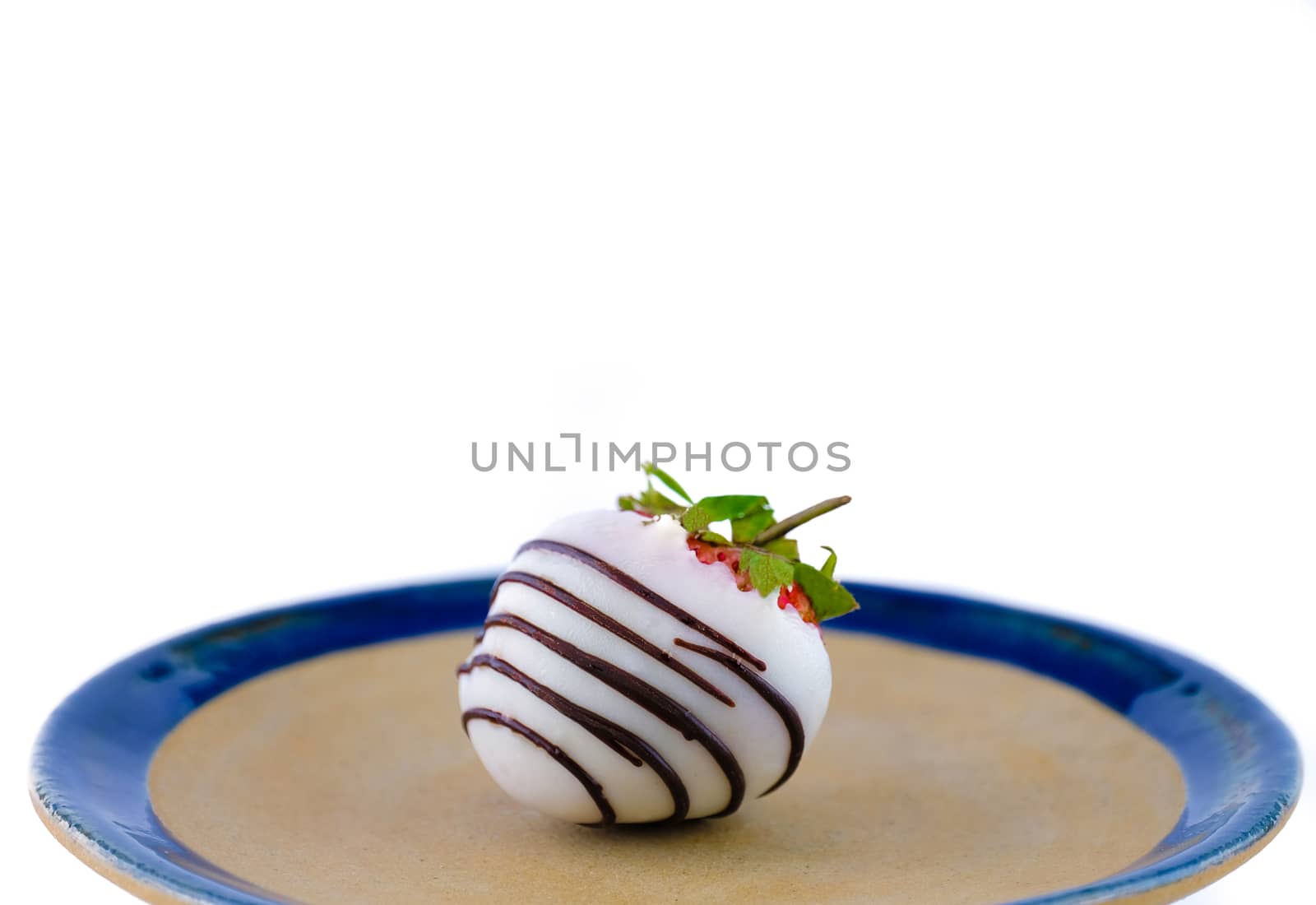 white chocolate coated strawberry on a ceramic plate, white background