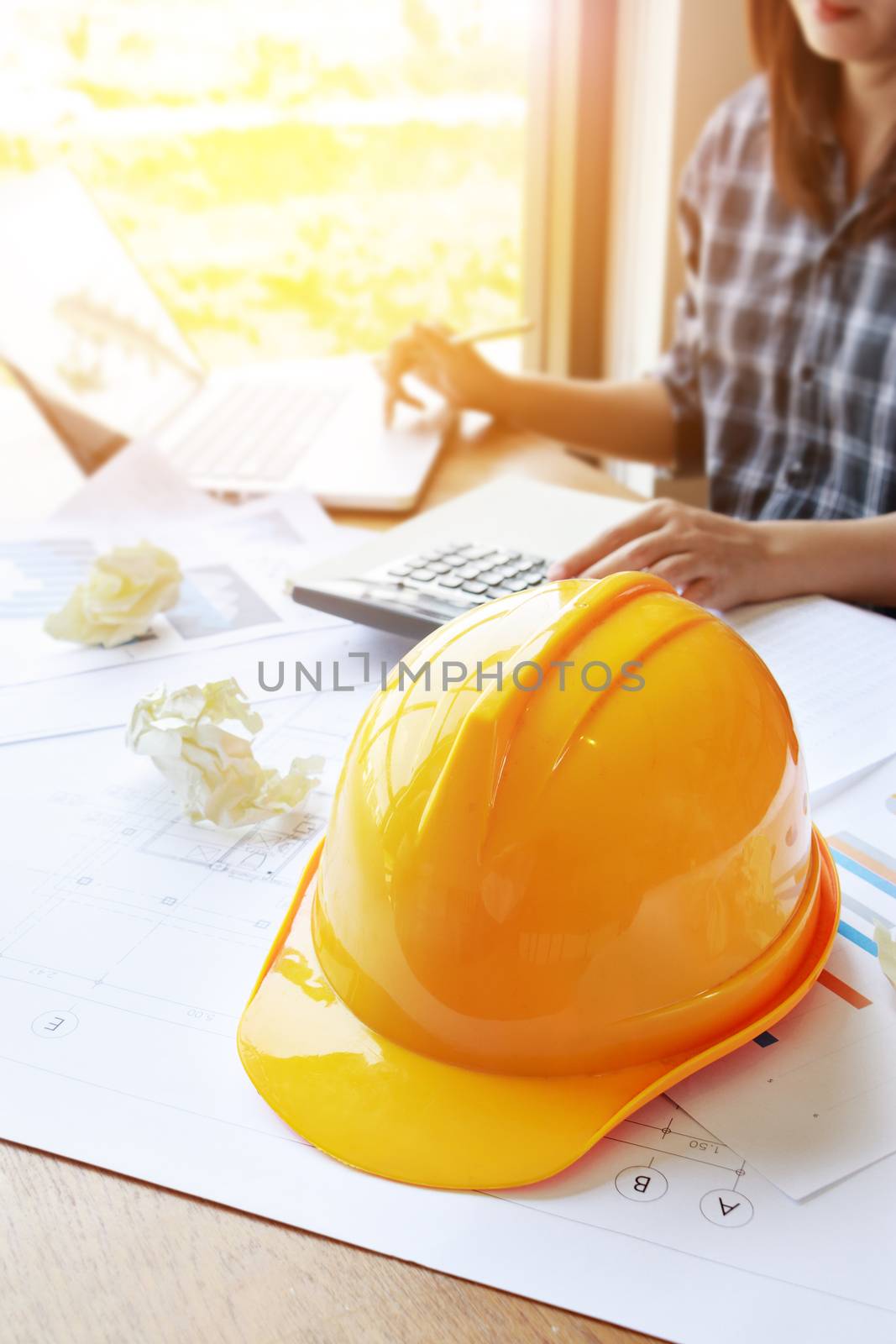 architect Asian woman working with laptop, calculator and blueprints. engineer calculate and inspection in workplace for blueprints architectural plan,sketching a construction project ,selective focus