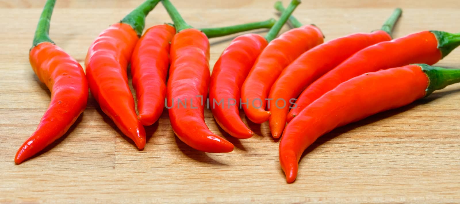 a bunch of fresh red hot chilli peppers isolated on wooden background