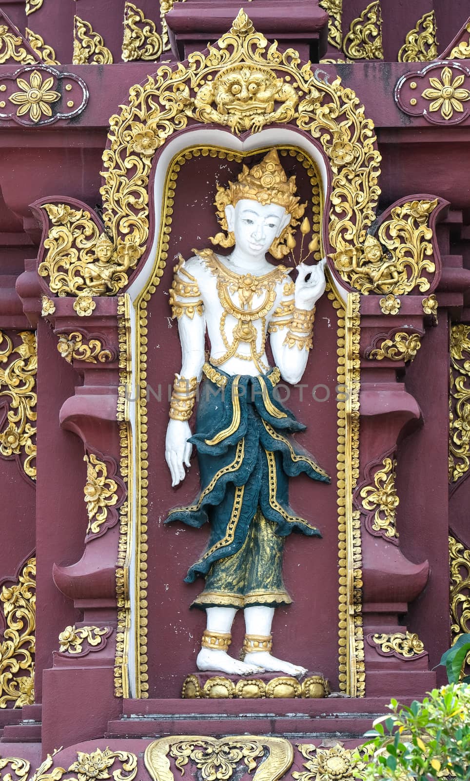 Thai stucco art with an angle dressed in garment painted with green and gold.