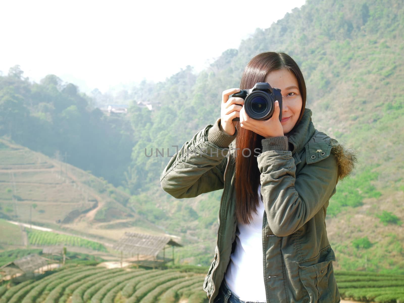 Asian tourist woman backpacker taking photo at mountain nature view ,Chiang Mai , Thailand on holiday vacation. tea plantation at background by asiandelight