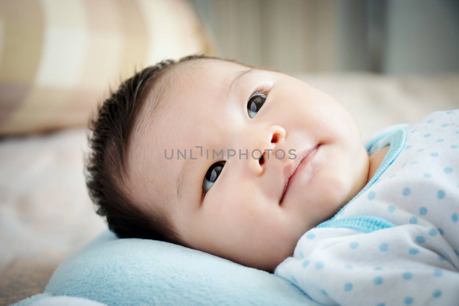 Asian baby portrait. cute Asian baby girl open eyes on the comfortable bed looking for parent on day time with little smile. happy children concept.