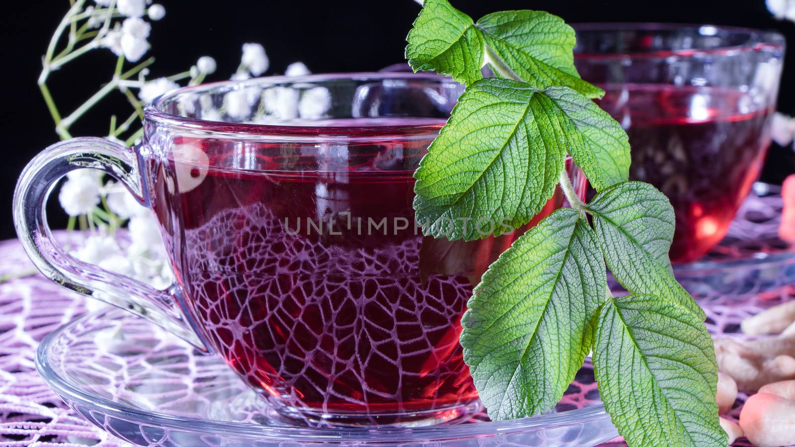 Hibiscus red tea mug with tea leaf or mint leaf close-up horizontal photo.Medicinal therapy on medicinal herbs and decoctions.Spicy herbs and medicinal broths.Relaxing and tonic drink.Zen tea ceremony