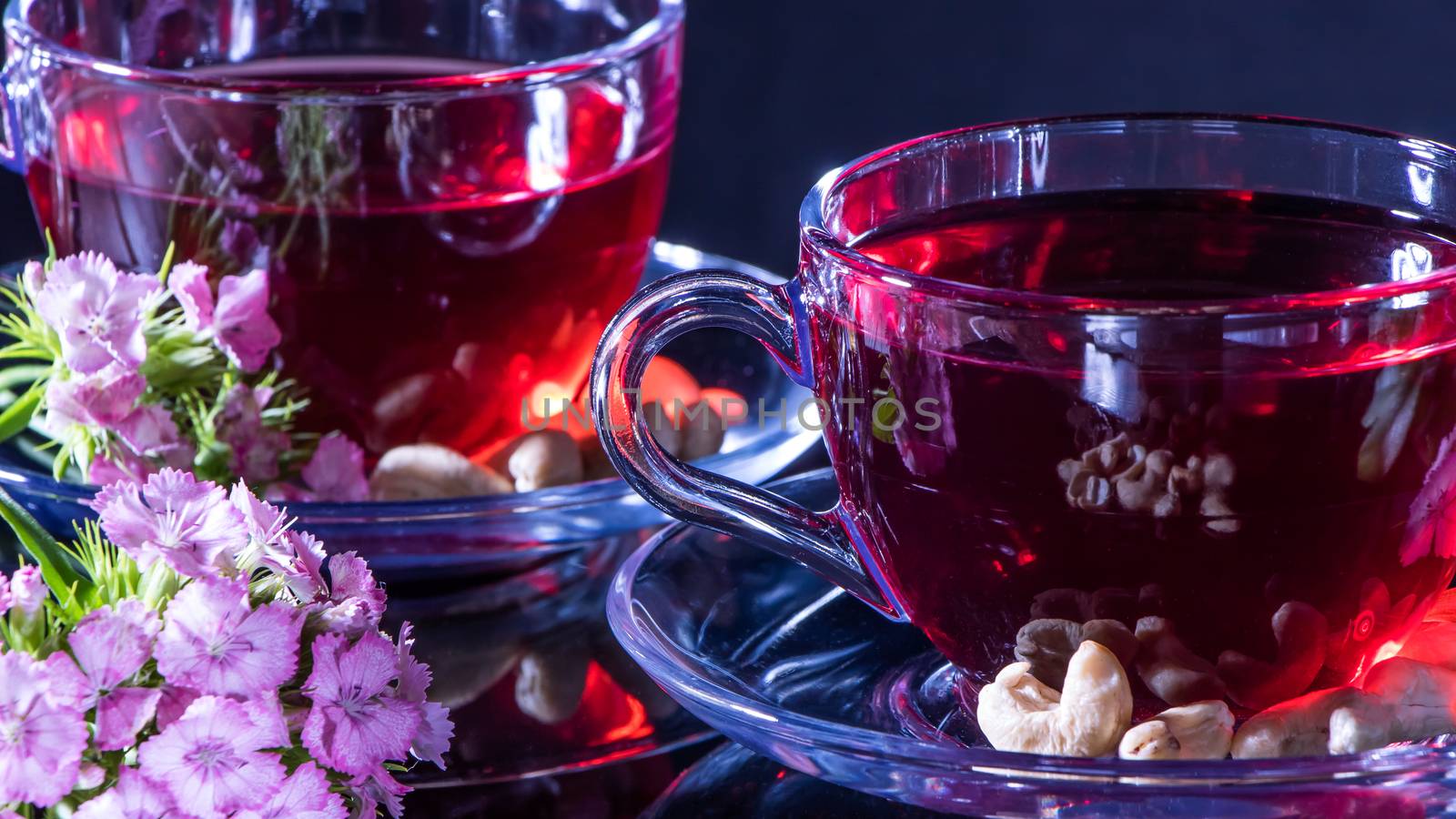 Hibiscus Red tea mug with carnation flowers close-up horizontal photo.English tea tradition.Medicinal therapy based on medicinal herbs and decoctions.Spicy herbs and medicinal broths.A relaxing drink
