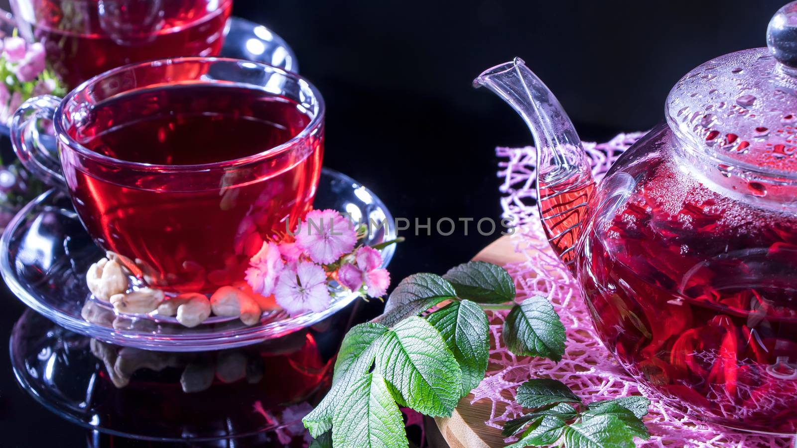 Hot luxury tea with a pleasant smell in a cozy home.Relaxing drink.Teapot, mugs of tea, cashew nuts, clove flowers and green medicinal leaves. Tea ceremonies and traditions in Japanese and Zen style