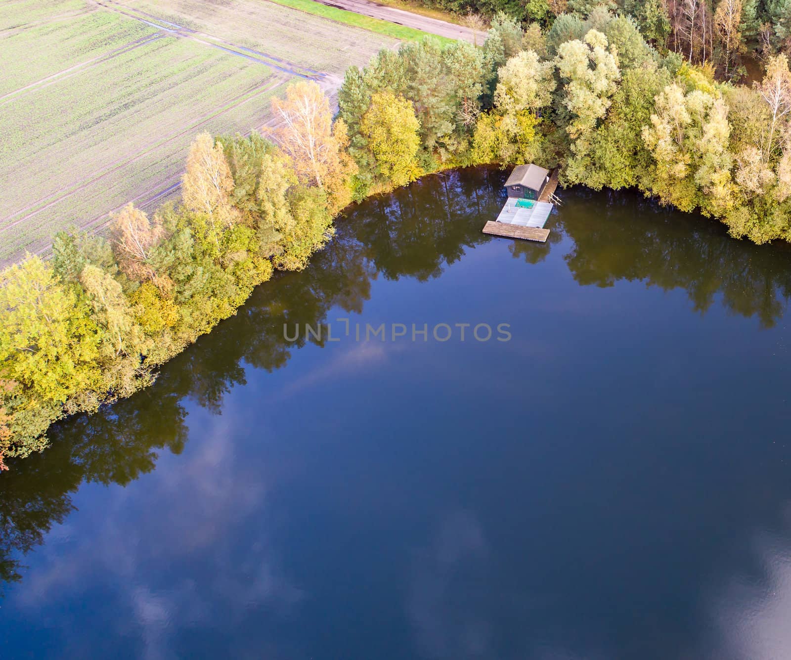 Fishing lodge in the corner of a pond, aerial view with drone