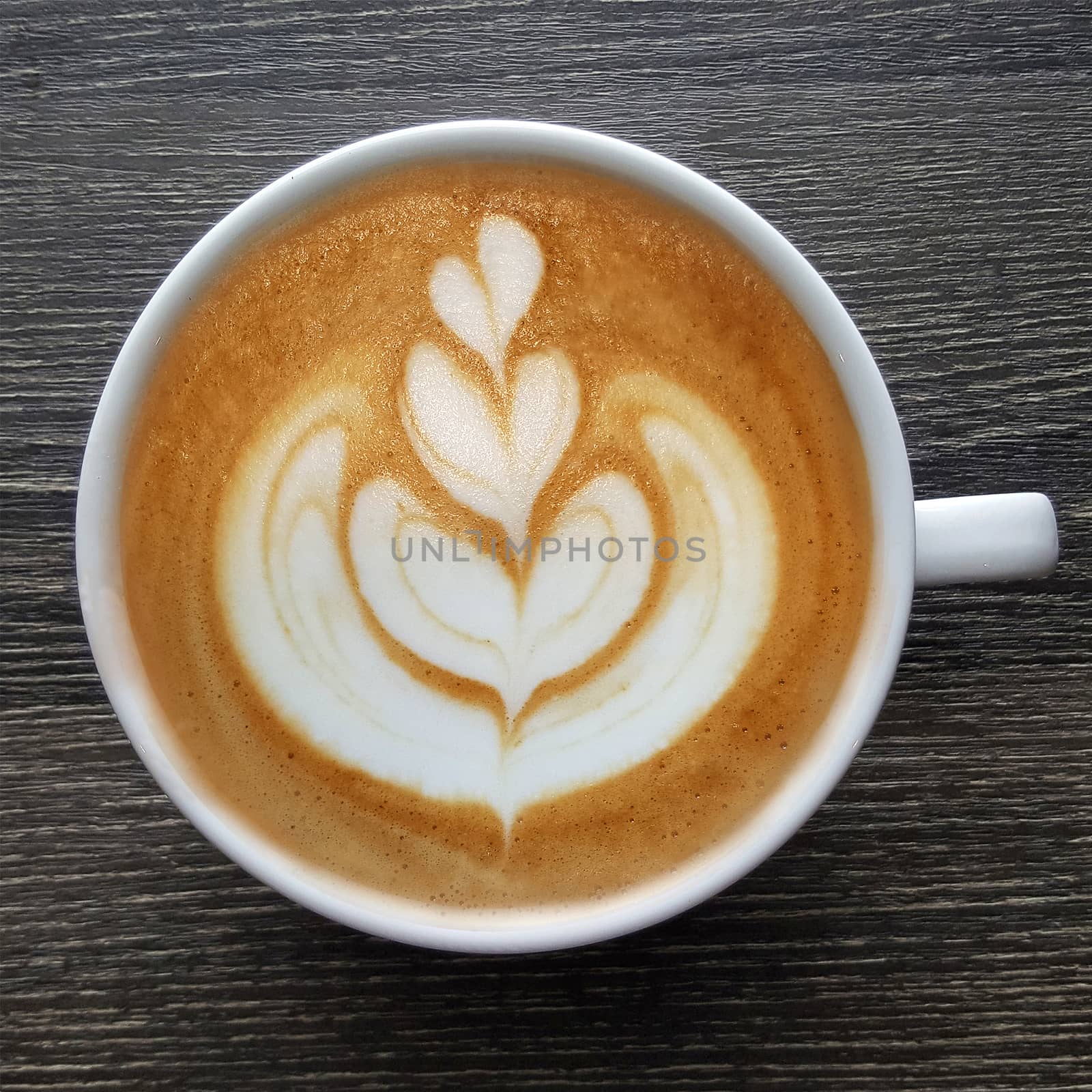 Top view of a mug of latte art coffee on timber background.