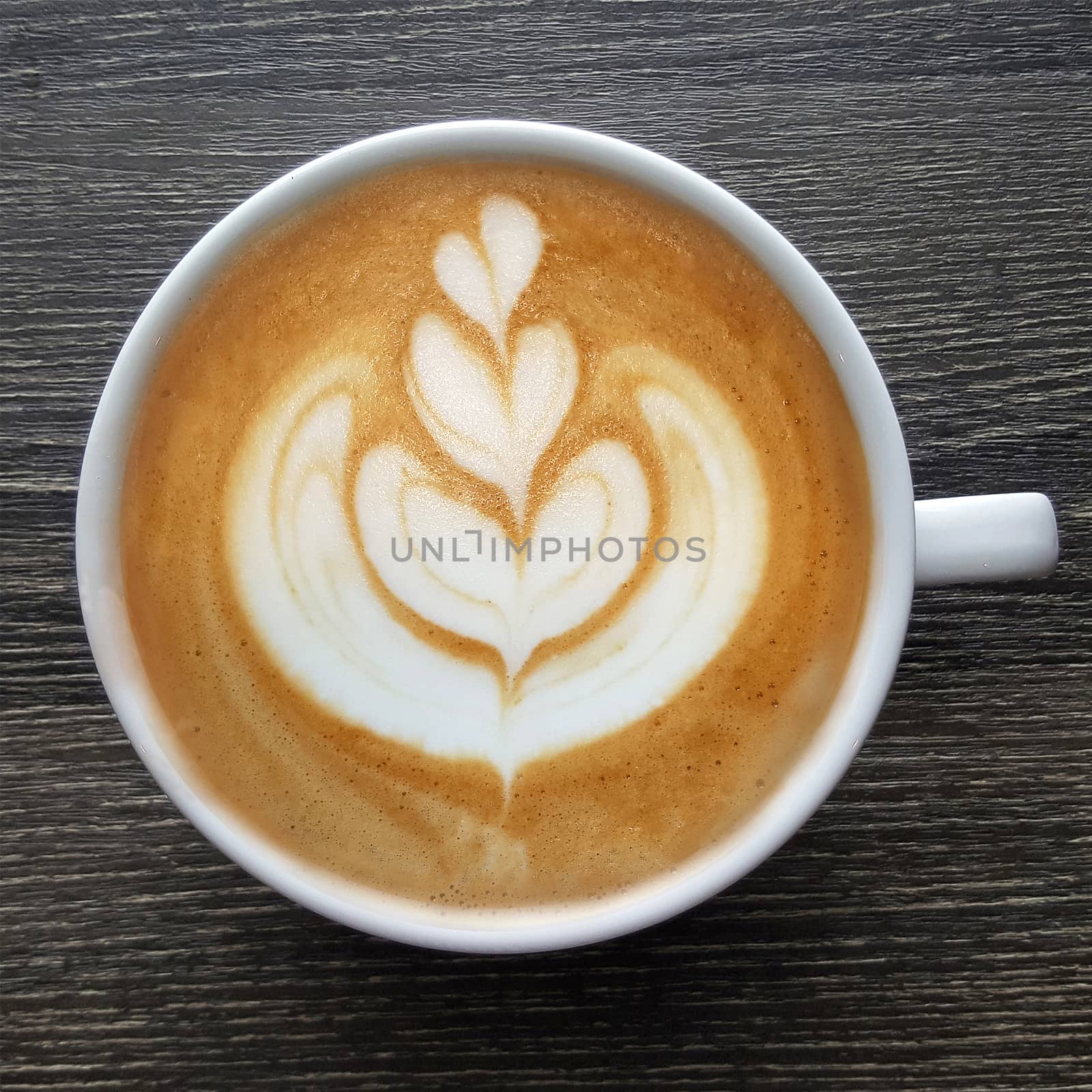 Top view of a mug of latte art coffee on timber background.