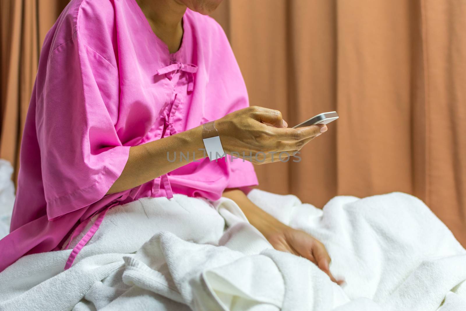 Patient asian woman with adhesive plaster on hand using smartphone for internet communication on patient bed in the hospital