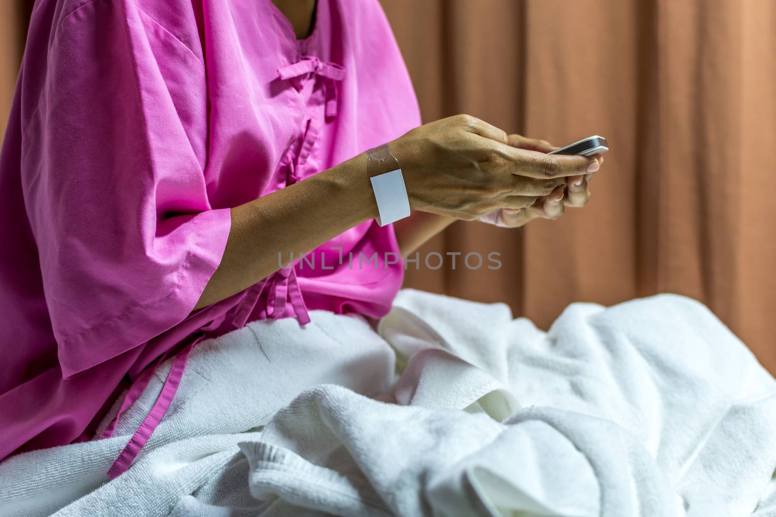 Patient woman using smartphone on bed by PongMoji