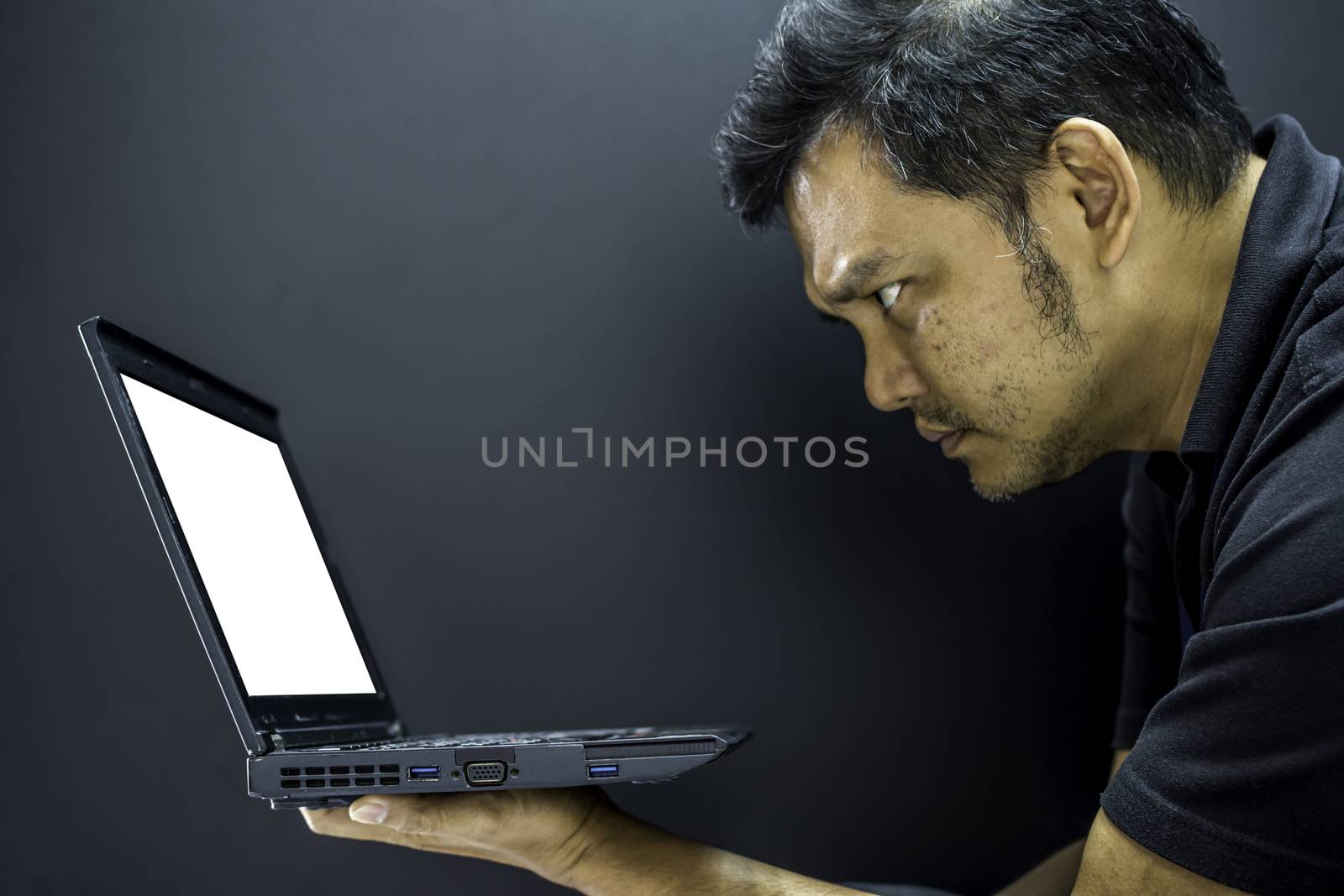 Asia man serious thinking when working and look at computer notebook with white screen for business concept on black background dark style