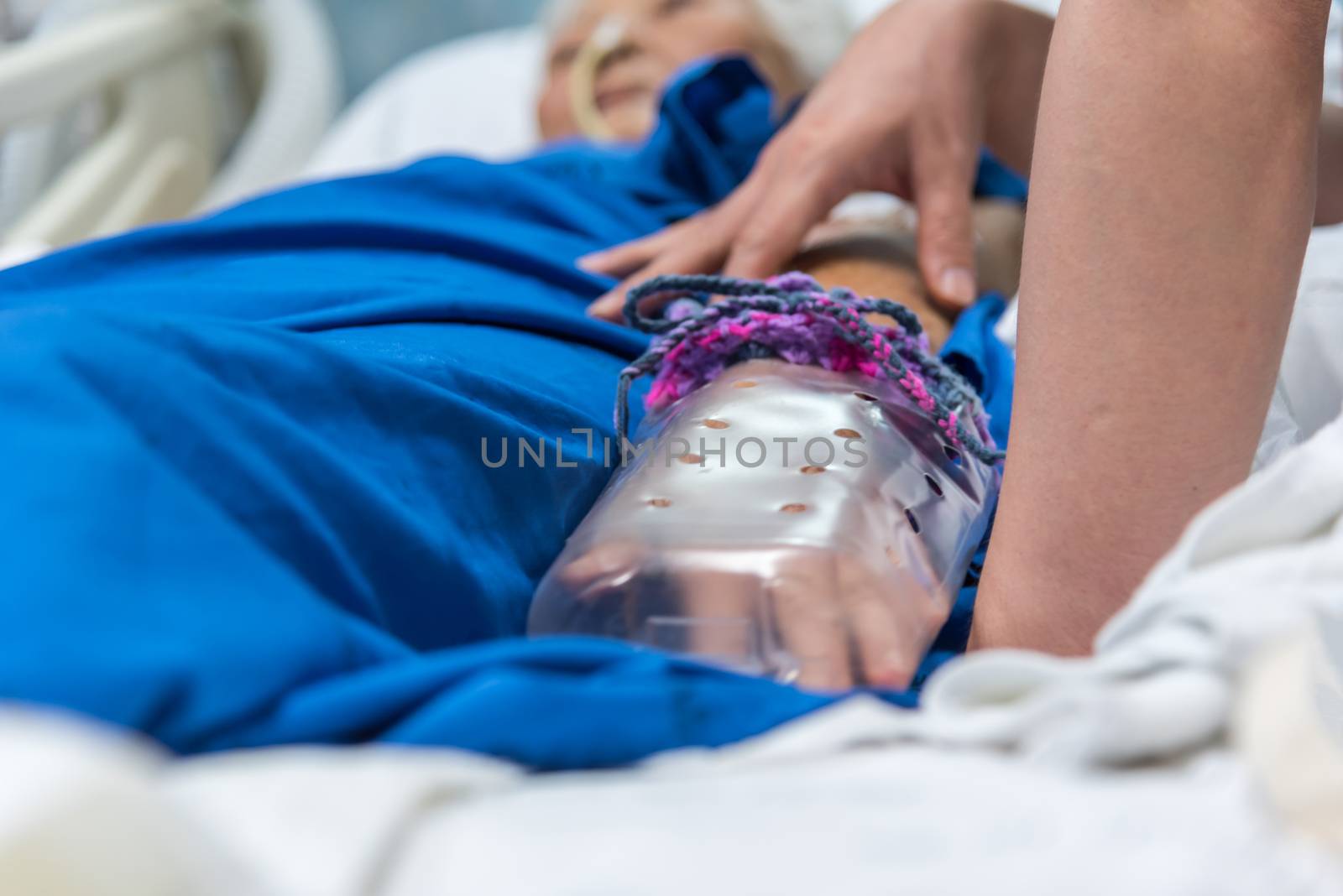 Patient in the hospital with saline intravenous and relatives patient hand holding a elderly patient hand with DIY restraint gloves