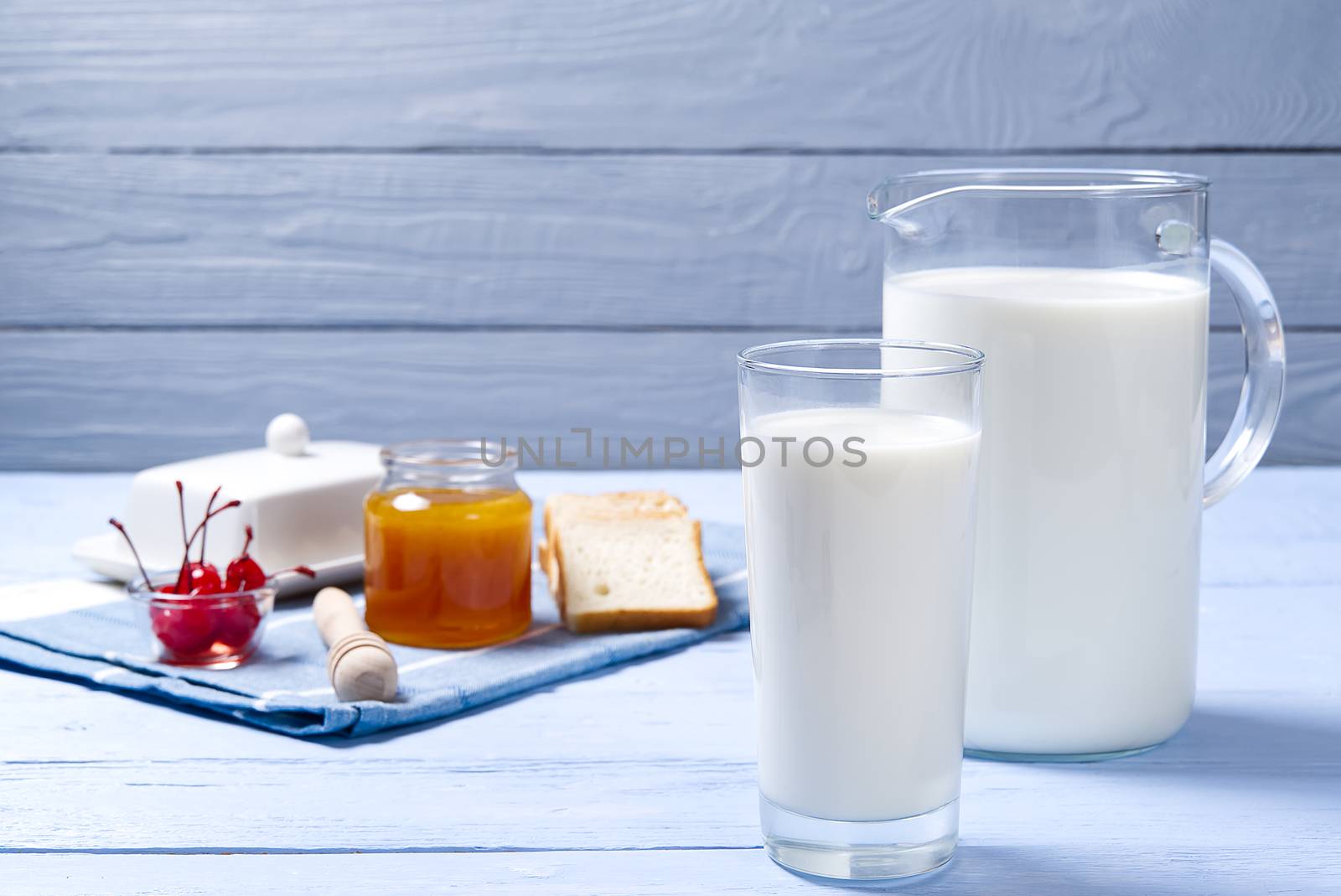 jug and glass of milk on a blue wooden background with cookies