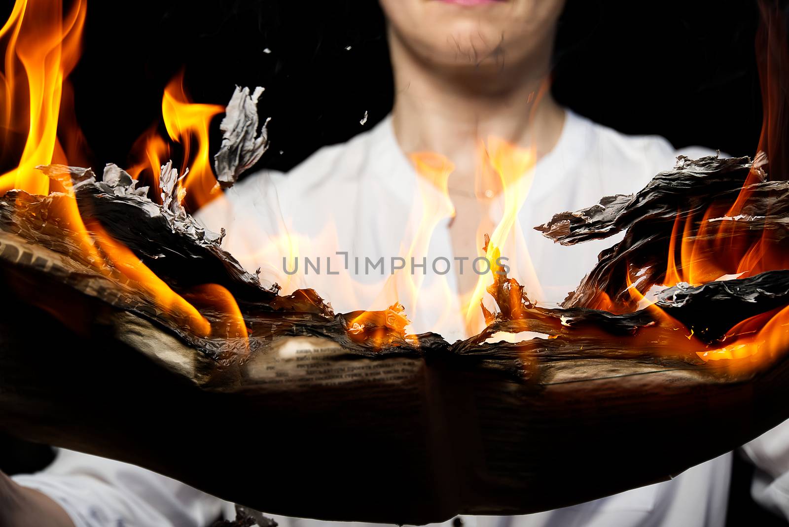 A woman is holding a burning newspaper. Fake news concept