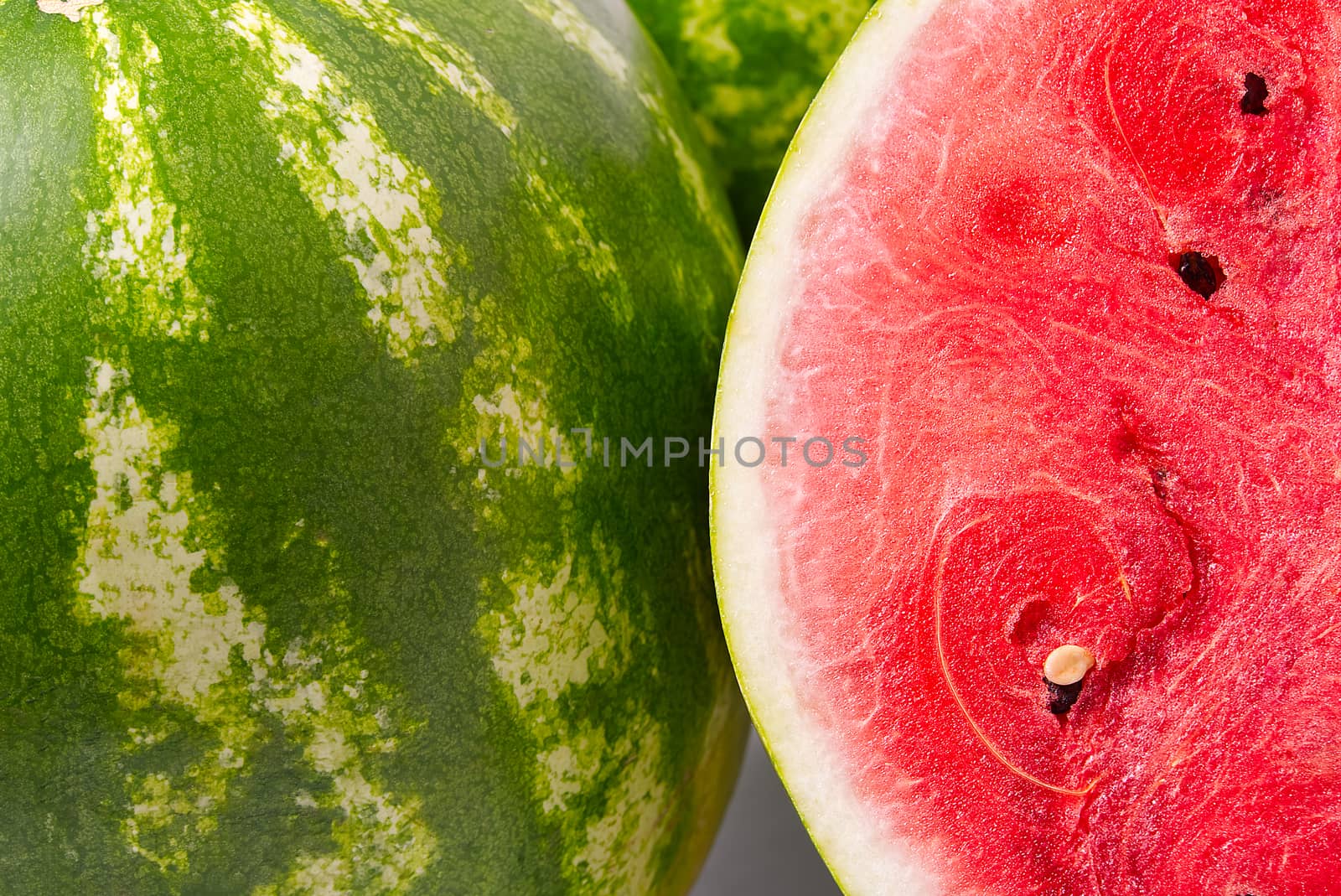 Fresh organic green watermelon and sliced half of watermelon with red texture, close-up