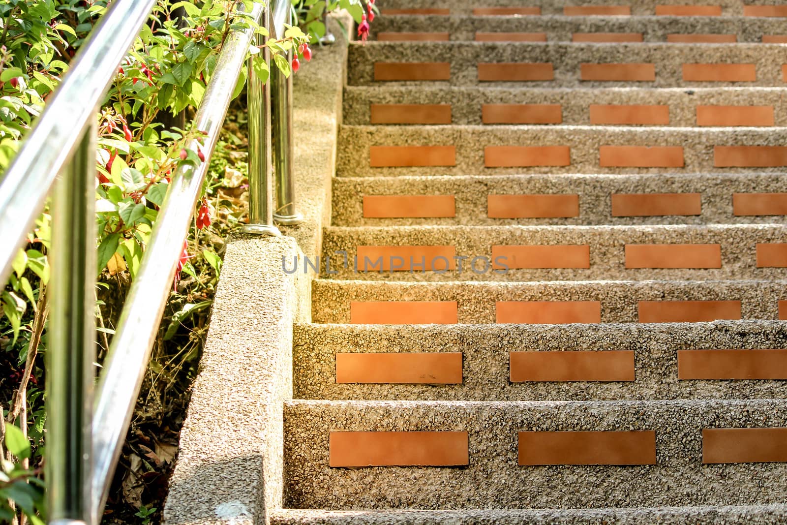 Exterior stairs created from orange brick with concrete and the handle is made of stainless steel.