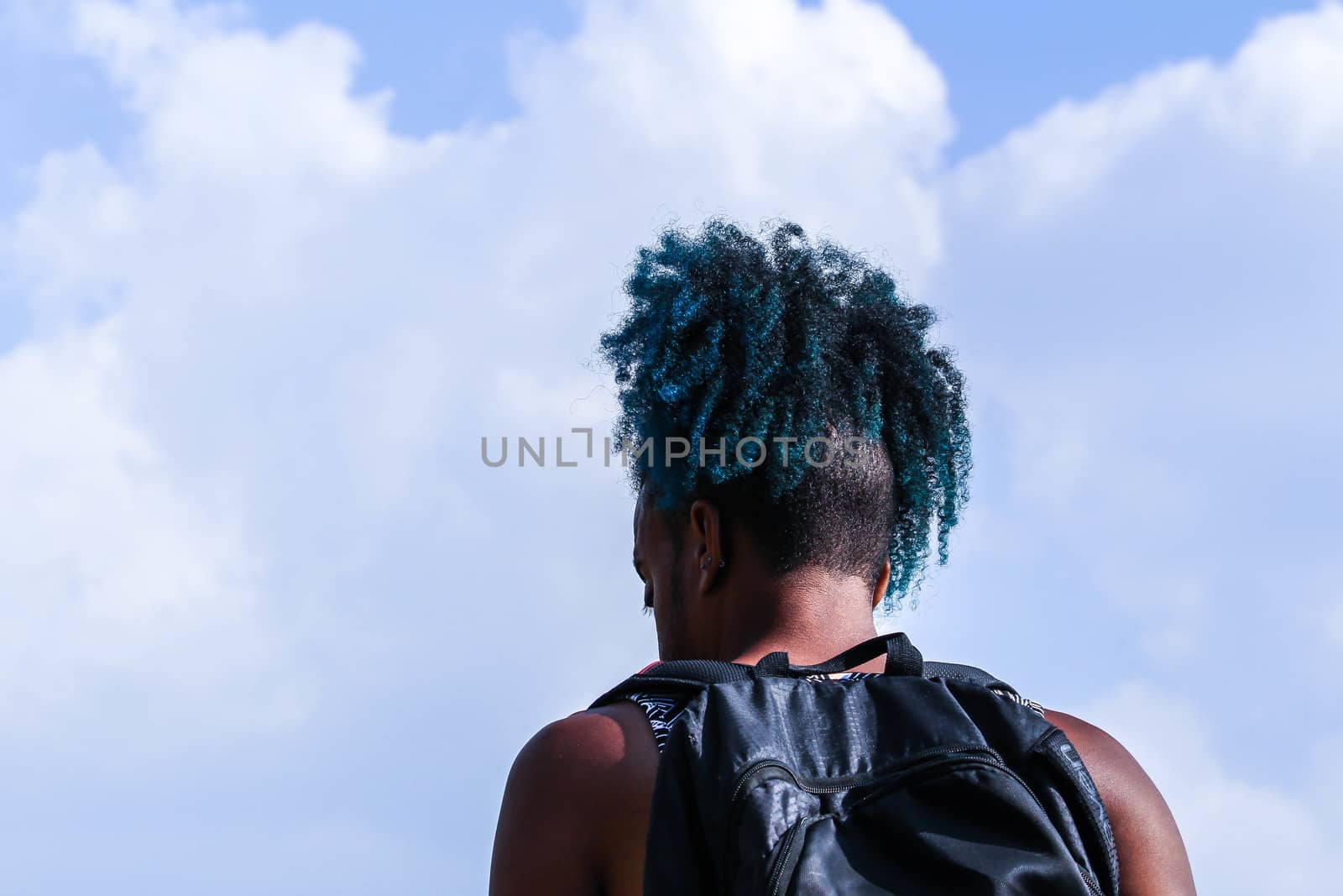 Rear view of young African man with backpack stand and blue sky background. Traveler concept.