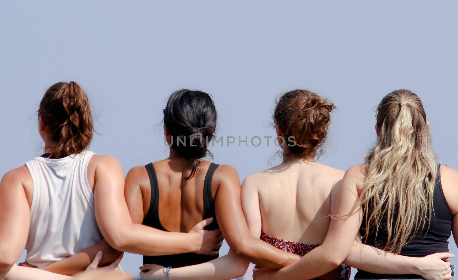 Rear view of group of friends hugging together for take a photo. Friendship concept.