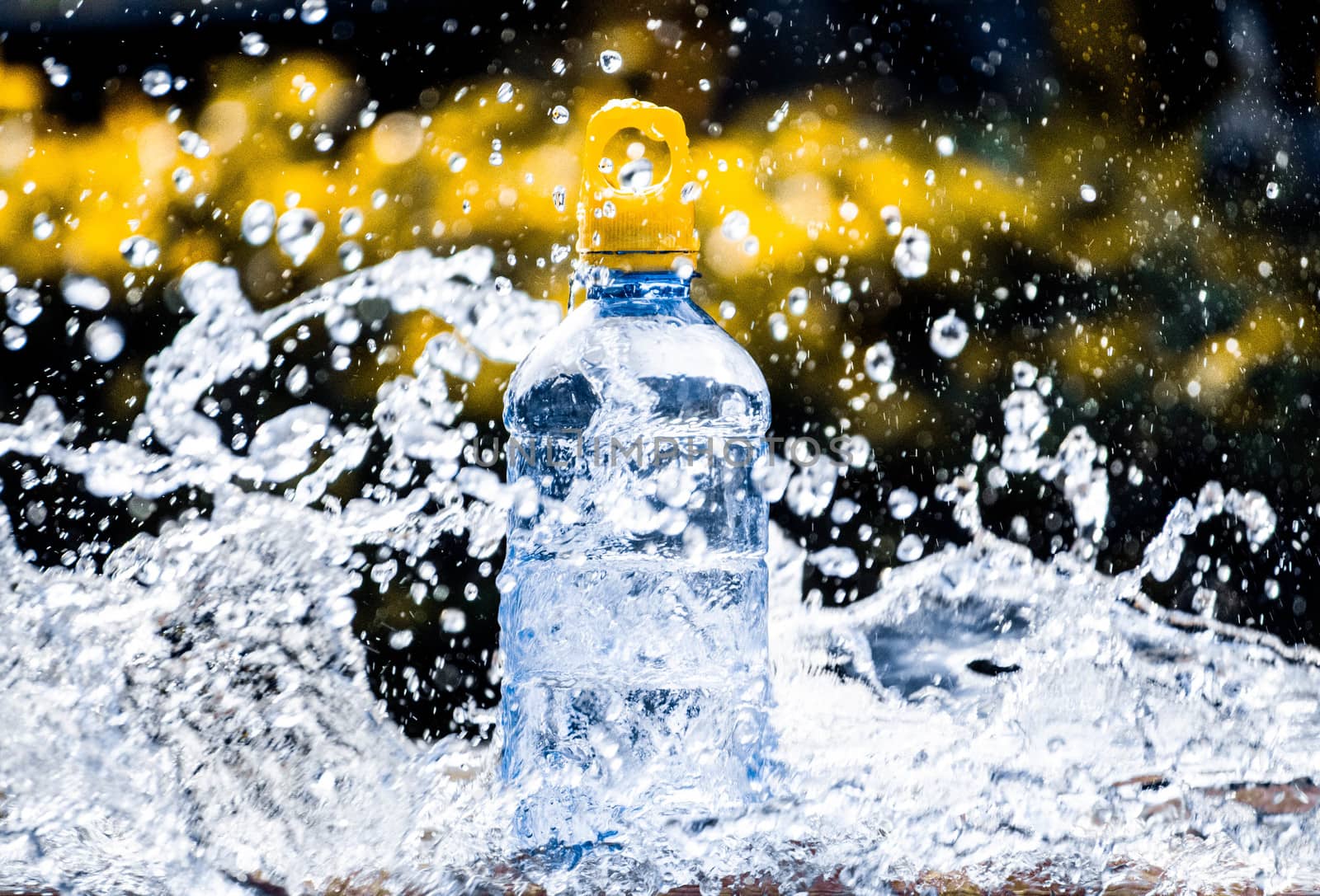 Fresh pure water splashing around of bottle with blurred background. Selective focus and space for text. by TEERASAK