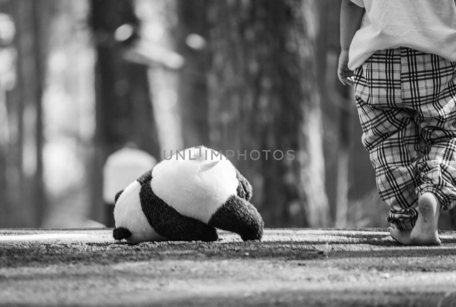 Rear of Asian little child girl walking barefoot and abandoned the teddy bear in solitude on the road. by TEERASAK