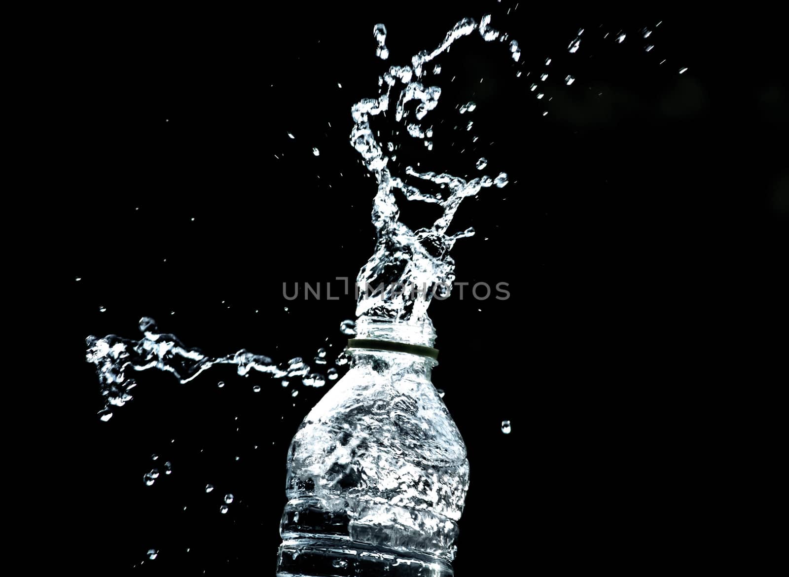 Fresh pure water splashing out of bottle on black background. Selective focus and space for text. by TEERASAK