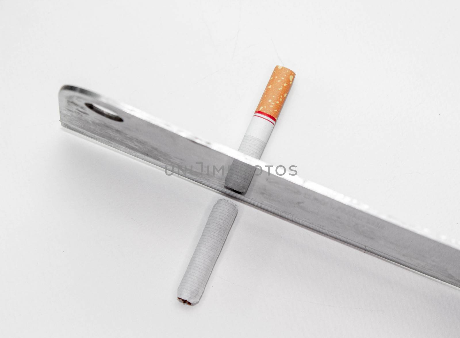 World No Tobacco Day; Use a knife to cut cigarettes isolated on white background. Cigarette destruction concept. by TEERASAK