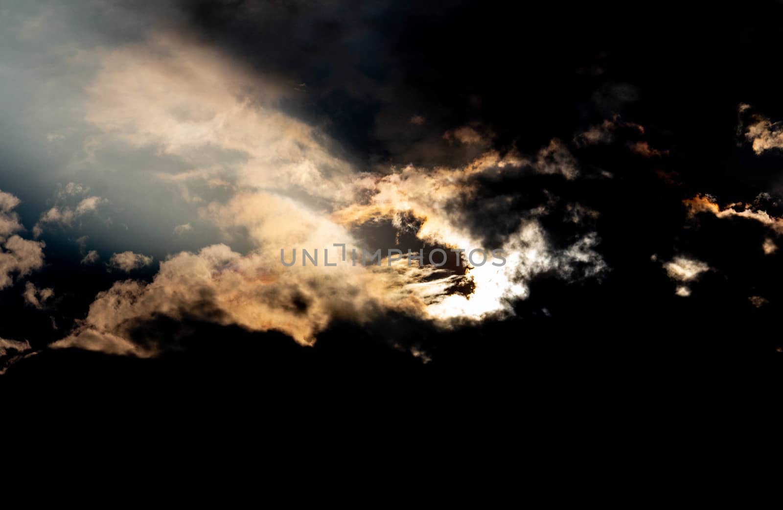 The Dark gray dramatic sky with sunlight through large clouds in rainy seasons. by TEERASAK