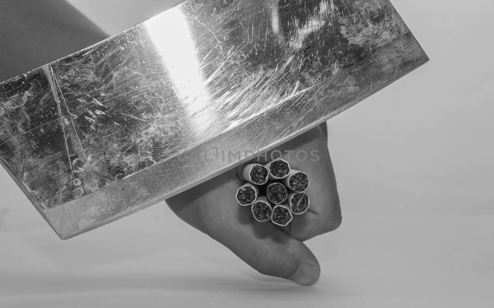 World No Tobacco Day; Use a knife to breaking cigarettes in hand isolated on grey background. Cigarette destruction concept.