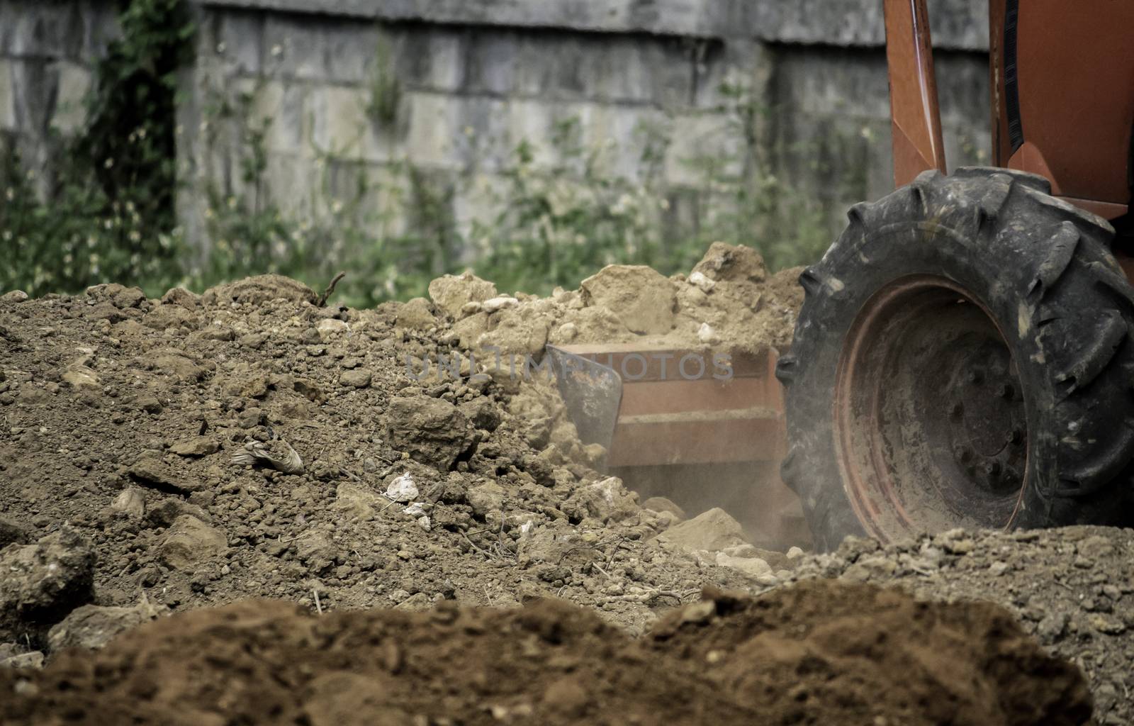 The tractors are adjusting the surface soil to smooth for construction. by TEERASAK