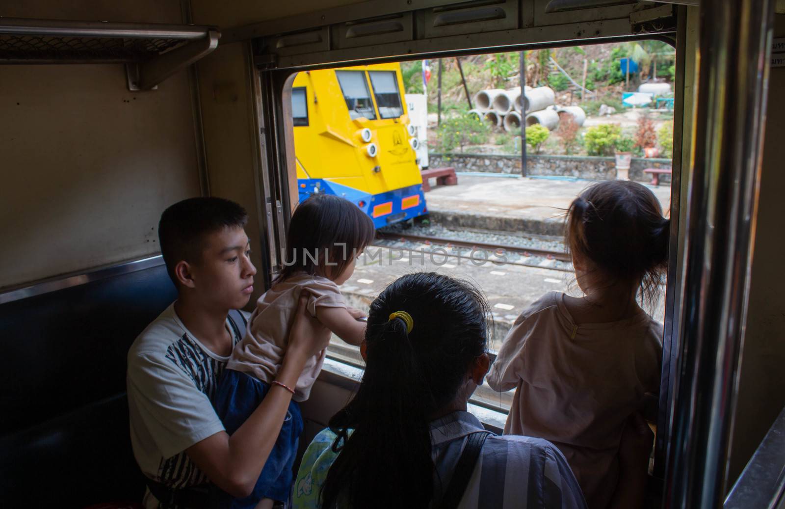 Asian family sitting on the train and looking to outside through the window.