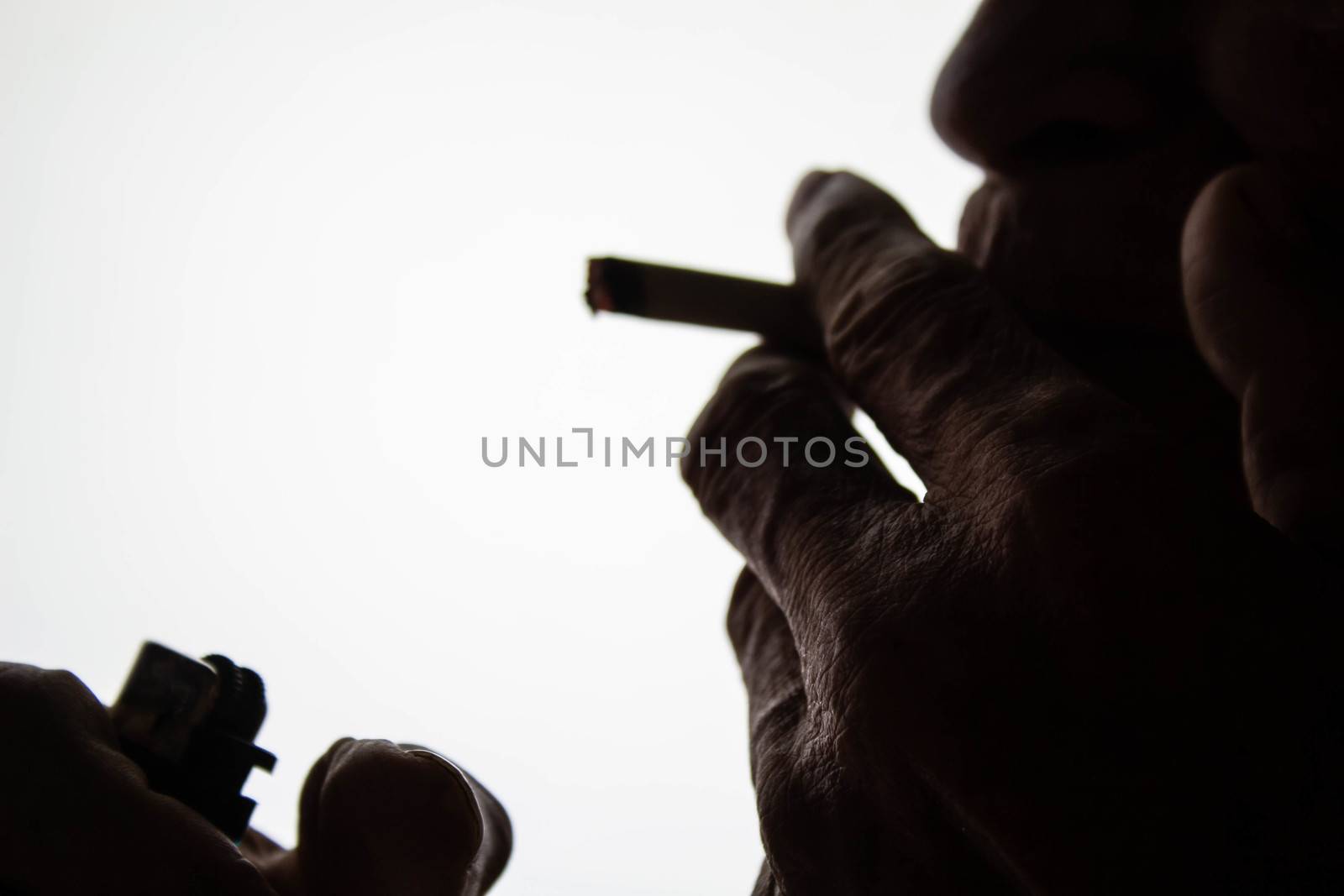 World No Tobacco Day; The silhouette of an elderly Asian man is smoking with space for idea text. by TEERASAK