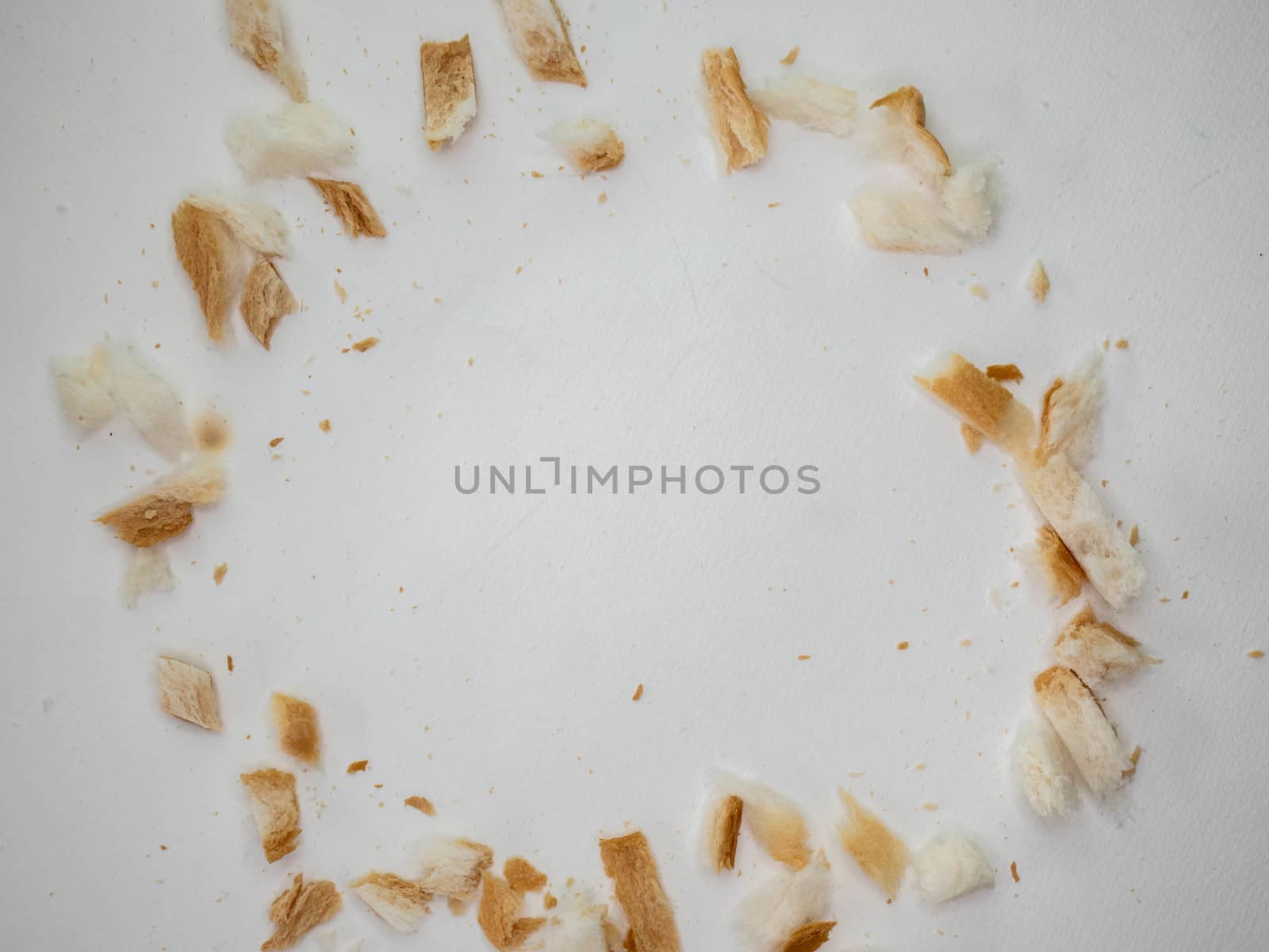 Scattered bread crumbs on white table background. by TEERASAK