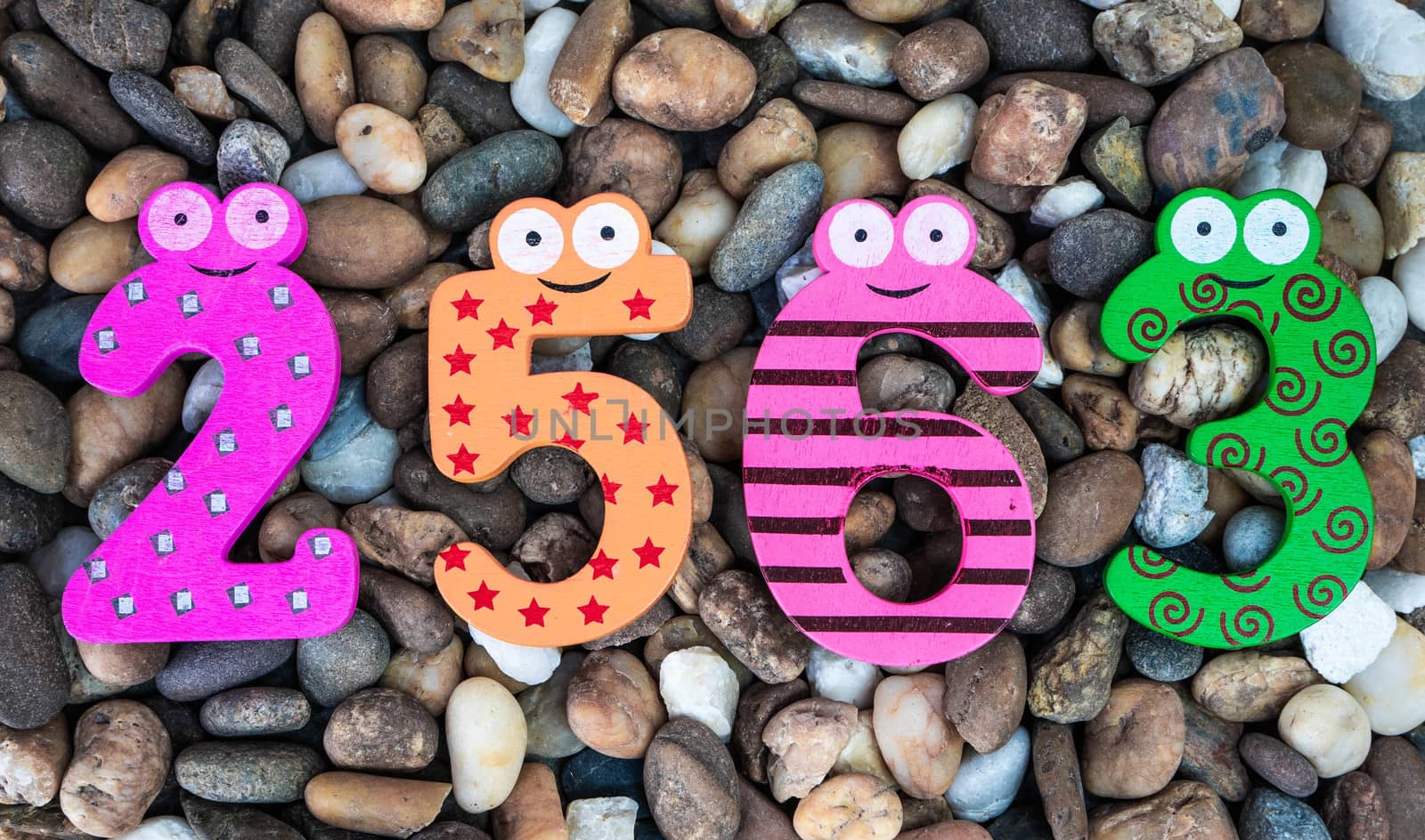 Pebbles pattern or small stones background in garden with colorful Arabic wooden numbers; 2563. Concept of new year and textured. by TEERASAK