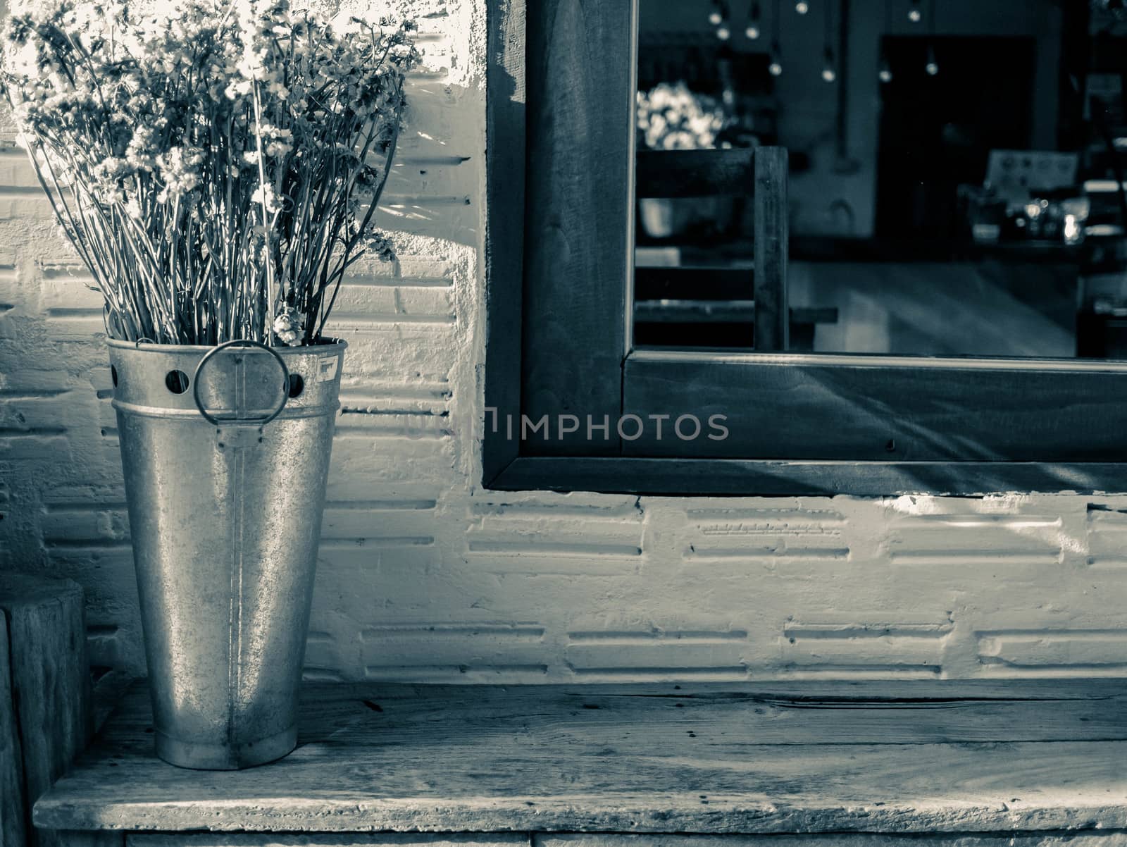 Dried flowers in stainless steel tanks on wooden chair nearing the window with sunlight in evening. Background concept. by TEERASAK