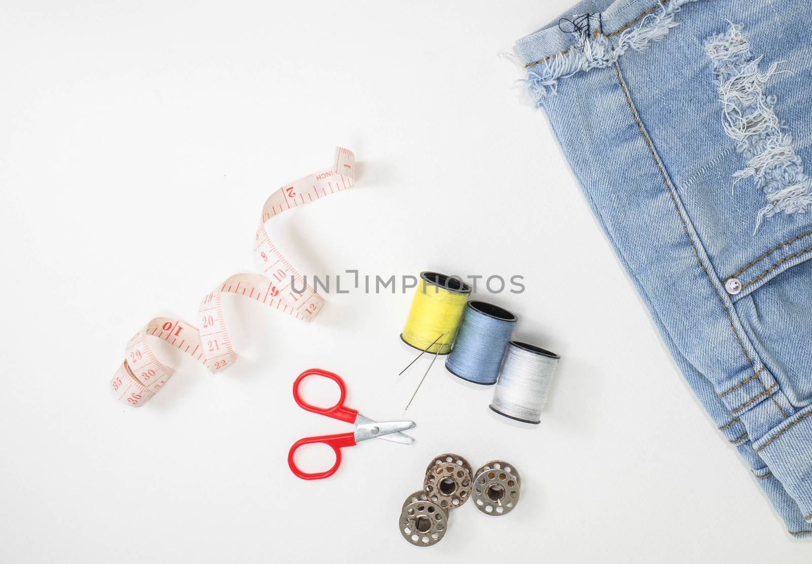 Sewing accessories and old jeans on a white background with place for text.