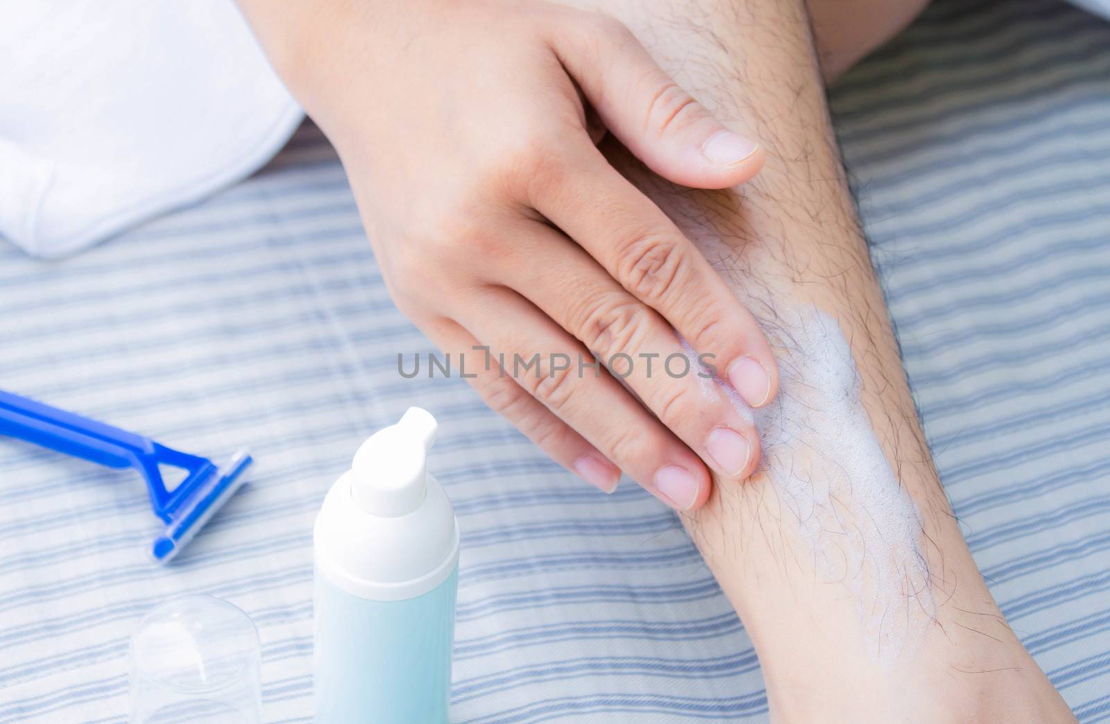 Close-up view of Asian woman shaving leg hair with blue razor and use foam to prevent injury. Body care and  Hair removal concept.