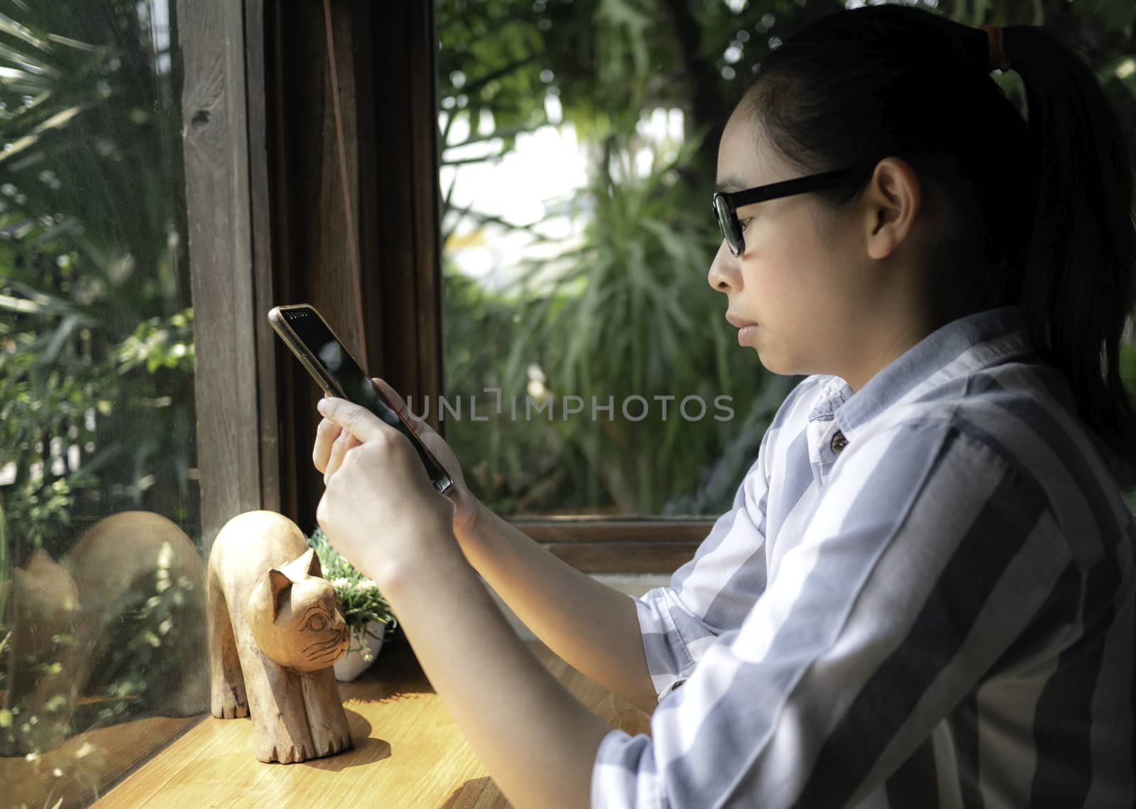 Confidenced business Asian young woman using smartphone to work while sitting in coffee cafe on weekend, Serious face. by TEERASAK