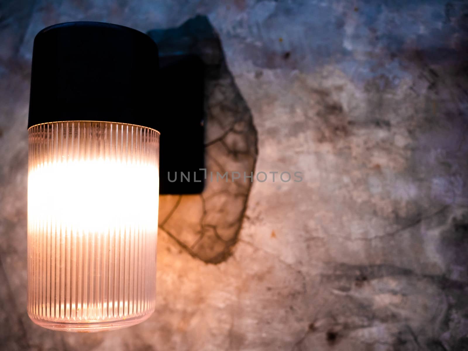 Modern Outdoor Lamp Mounted on the grey concrete wall background and black shadow with space for text. by TEERASAK