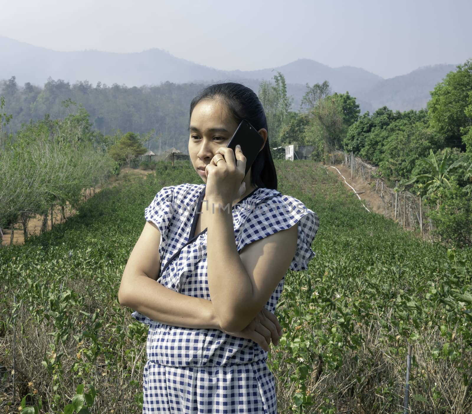 Asian young women talking by phone in the jasmine garden by TEERASAK