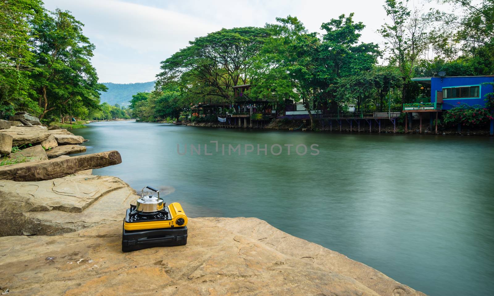 Picnic gas stove and aluminum teapot for boiling water near the river