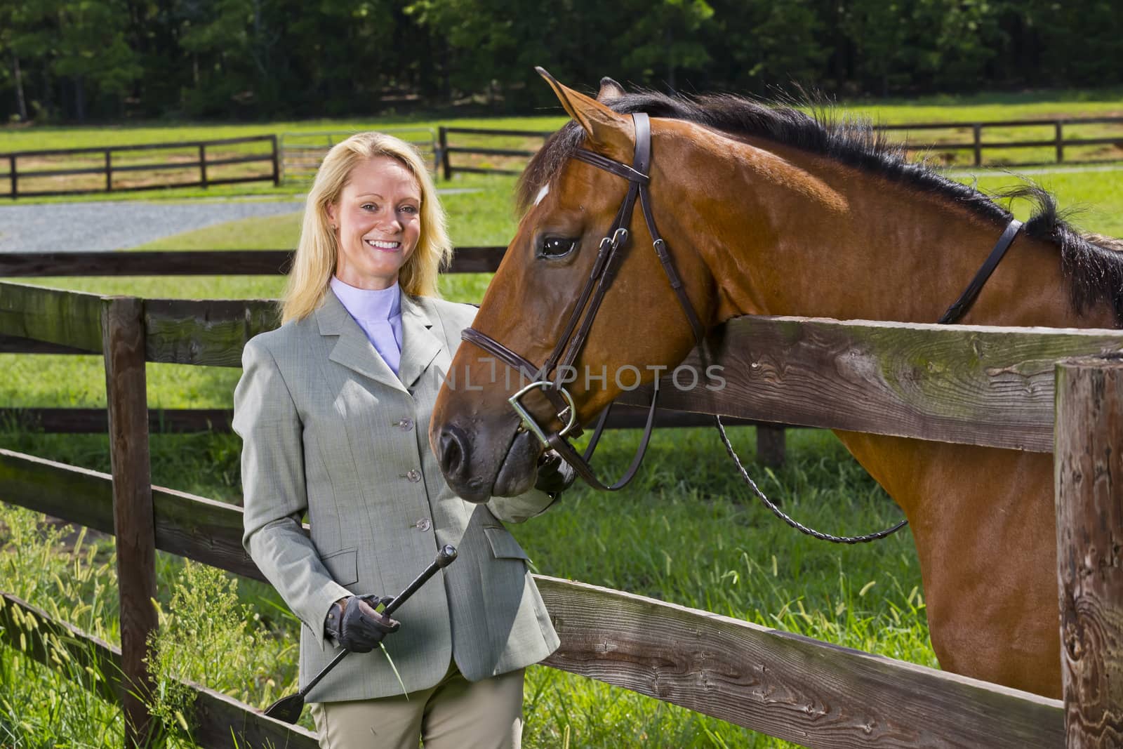 A blonde equestrian model poses outdoors before a horse show