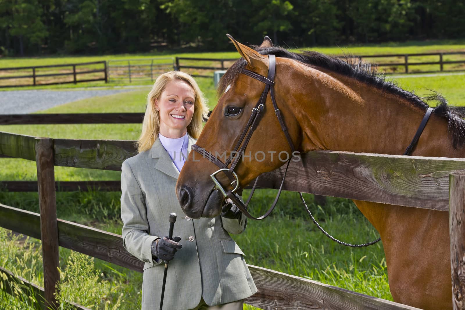 A blonde equestrian model poses outdoors before a horse show